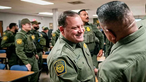 Chief Banks smiling and shaking hands with fellow USBP officers.